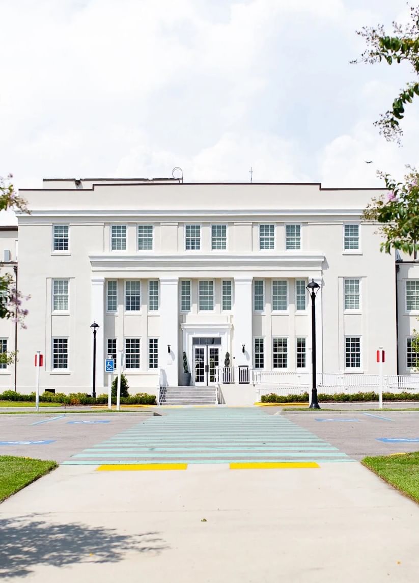 The grand white historic hotel main entrance building with large columns and a striped crosswalk at Centennial Plaza Resort