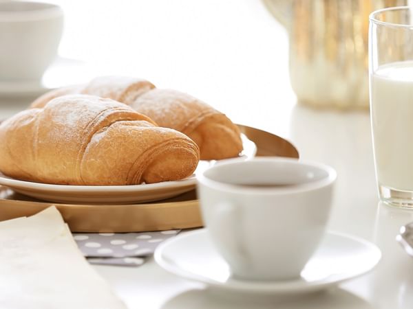 Croissants, milk, and coffee on a table highlighting free breakfast at Coast Whitecourt Hotel in Whitecourt.