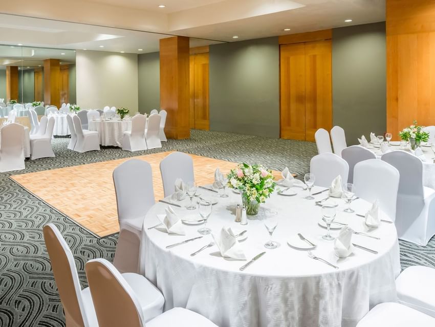 Tokio Venue featuring round tables with white linens and a light wood dance floor at Real Inn Perinorte