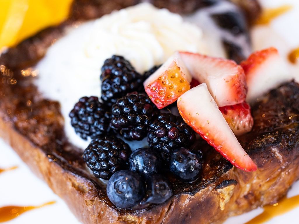 French toast topped with blueberries, blackberries, and whipped cream served in ALK at The Godfrey Hotel Hollywood