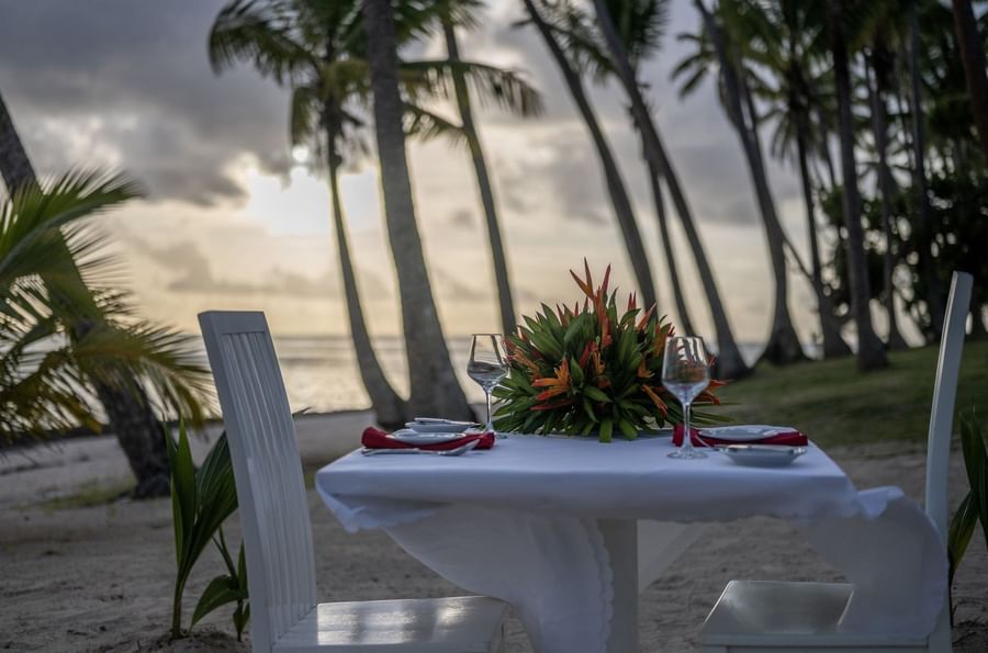 White dining table with a floral centerpiece by the beach in Tambua Restaurant at Tambua Sands Beach Resort