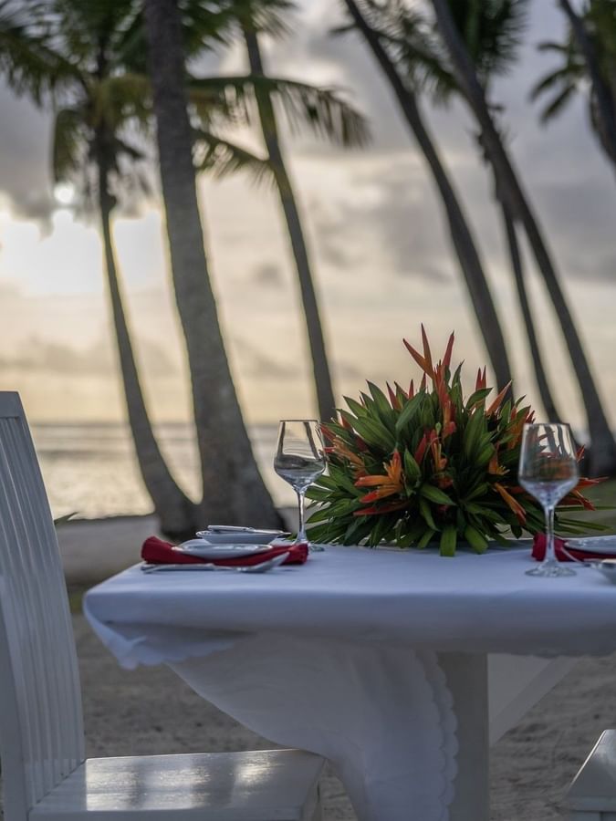 White dining table with a floral centerpiece by the beach in Tambua Restaurant at Tambua Sands Beach Resort