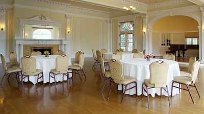 Music room with round tables adorned with white tablecloths at The Stanley Hotel