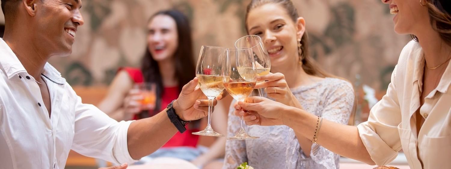 Friends toasting wine at an outdoor table in The Marke Kitchen at Novotel Sydney International Airport