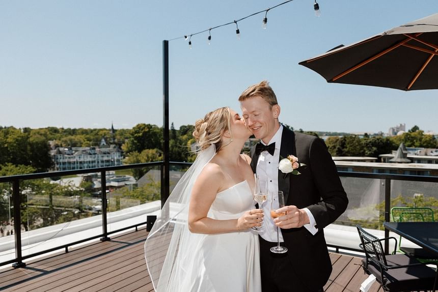 Wedded couple kissing by the rooftop reception at The Earl