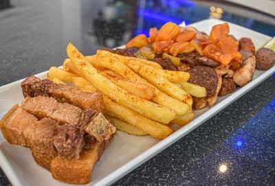 Un plato de frituras que incluyen papas fritas y trozos de cerdo en Velero Sports Bar en el Hotel Dann Carlton Barranquilla