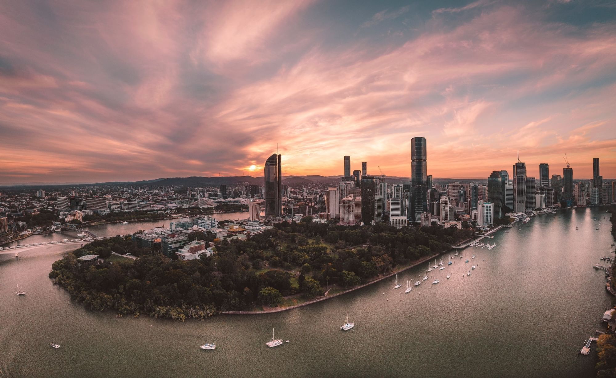 Aerial view of Brisbane City at sunset with a winding river with boats near Sofitel Brisbane Central