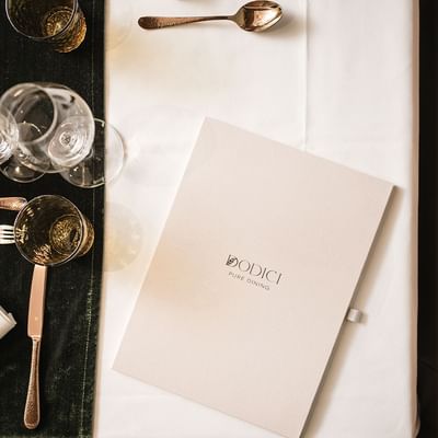 A table setting with glassware, cutlery, a folded napkin, and a menu card reading 