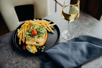 Delicious salmon sandwich served with a side of crispy fries and a glass of white wine at The Boulevard Inn & Bistro