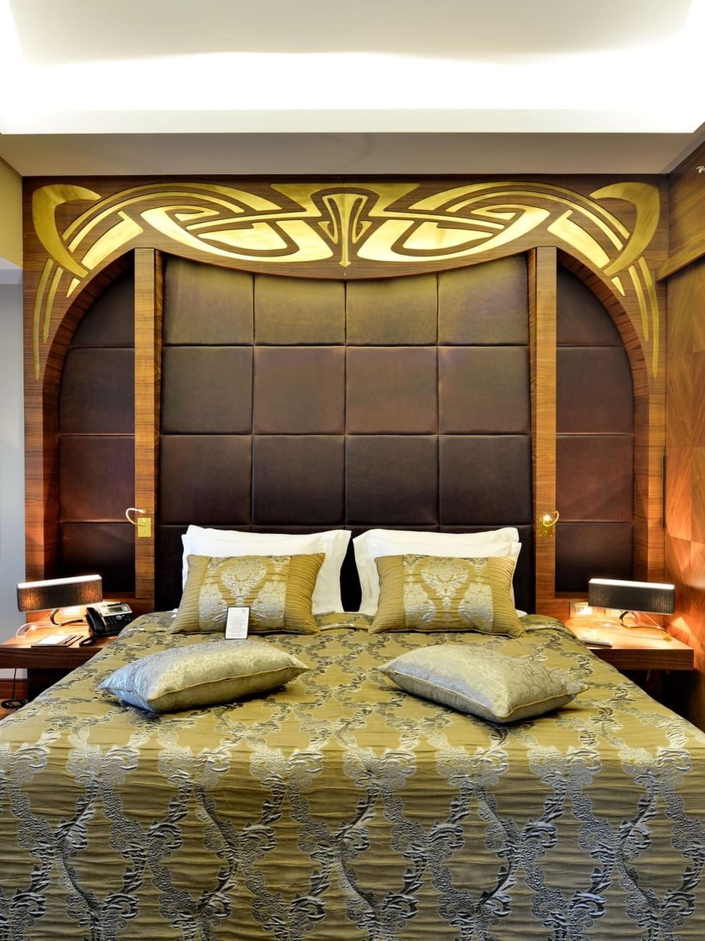 Gold patterned bed by a sofa under an ornate carved headboard in Ankara Suite with Terrace at Warwick Ankara