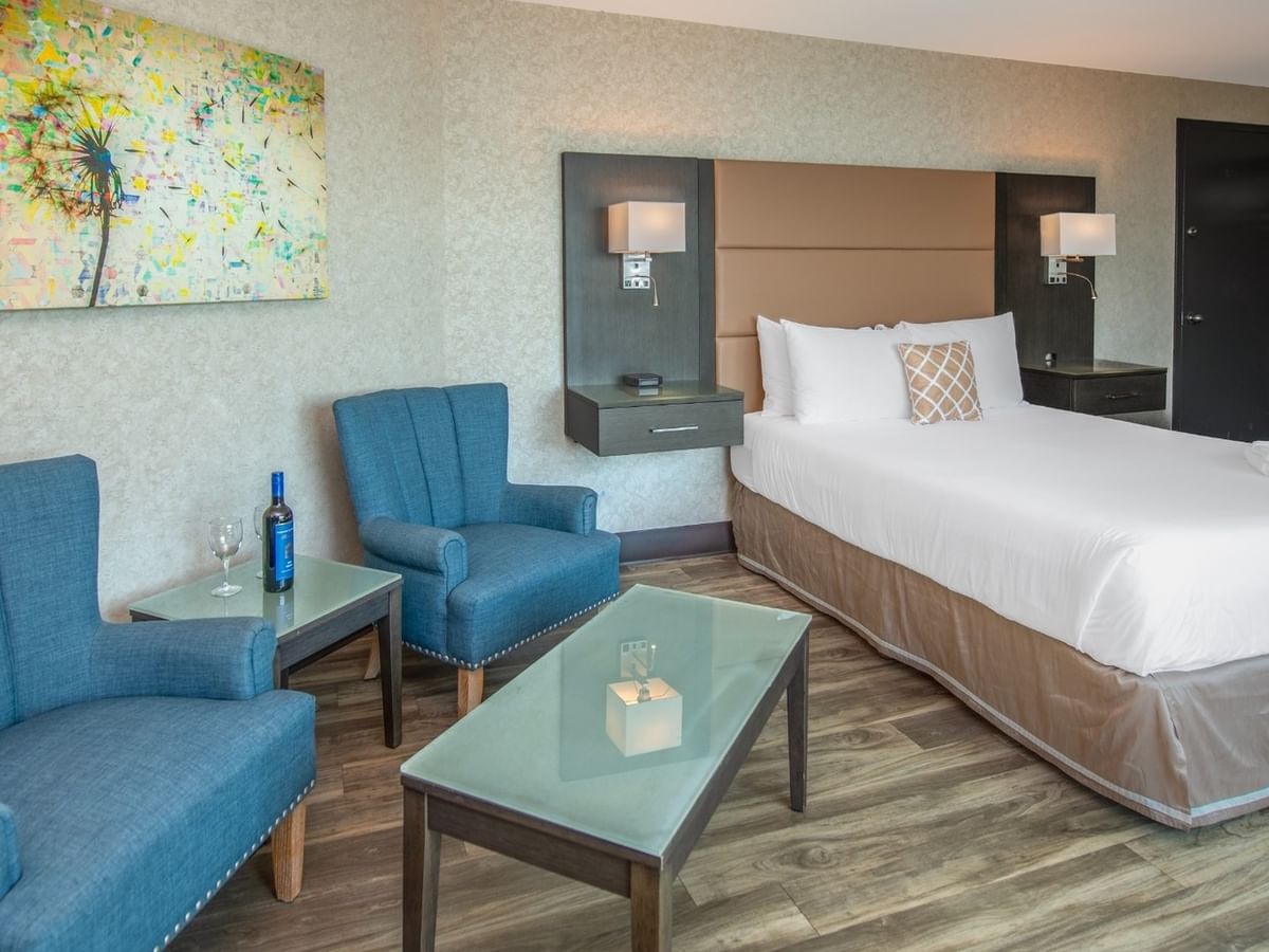Coast Premium King room with a king bed, two chairs, coffee table, and abstract wall art at Coast Lonsdale Quay Hotel