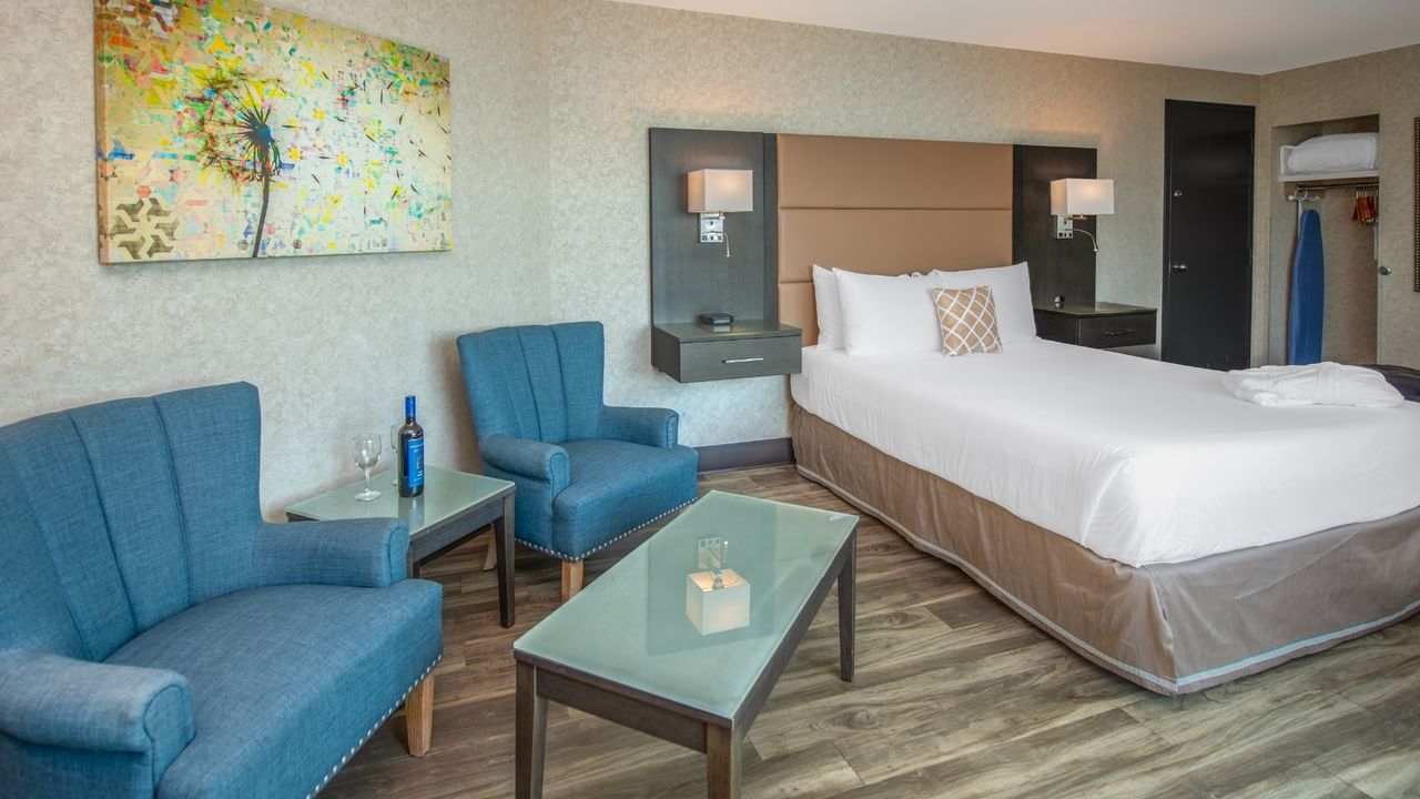 Coast Premium King room with a king bed, two chairs, coffee table, and abstract wall art at Coast Lonsdale Quay Hotel