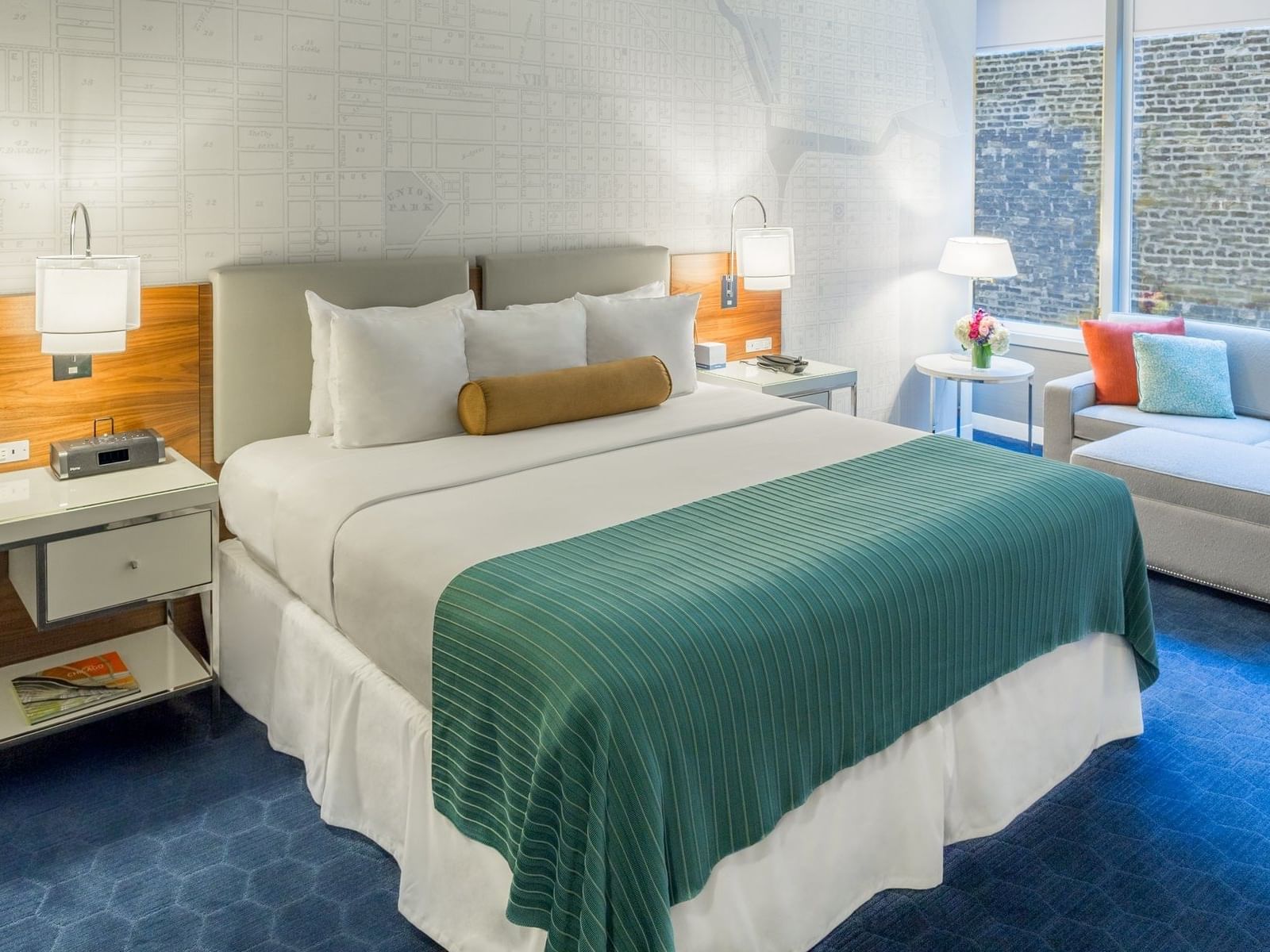Bed, nightstands & a sofa in Deluxe King Room at Kinzie Hotel