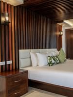 King bed by a dark wood-slat wall under a ceiling with rolled towels in Warwick Suites at Warwick Fiji Resort and Spa