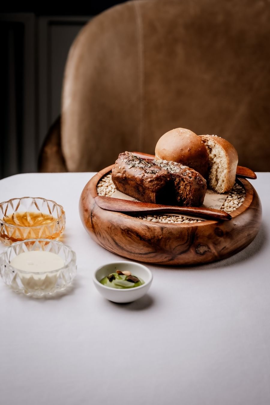 Freshly baked artisan bread in a wooden bowl surrounded by small dishes at The Capital Hotel, Apartments and Townhouse
