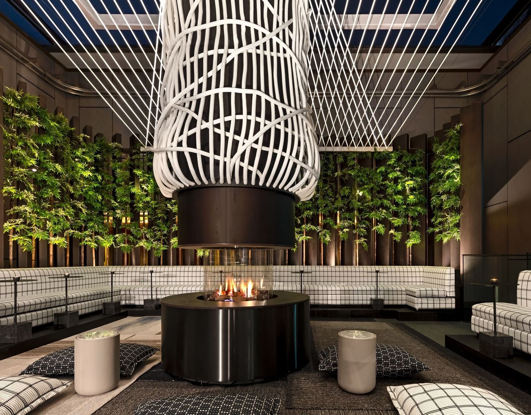 Elegant lounge area of 8 at The Londoner rooftop bar with a modern fireplace, comfy seating, and a unique ceiling design