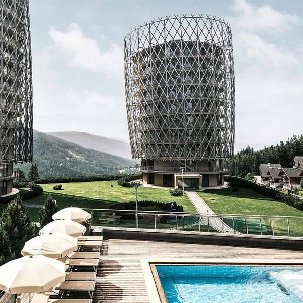 Blick auf architektonisch einzigartige Gebäude und einen Pool in einem landschaftlich schönen Resort.