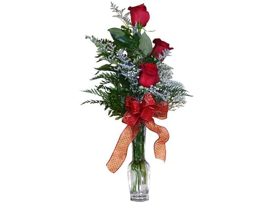Three roses arranged in a vase with a red bow