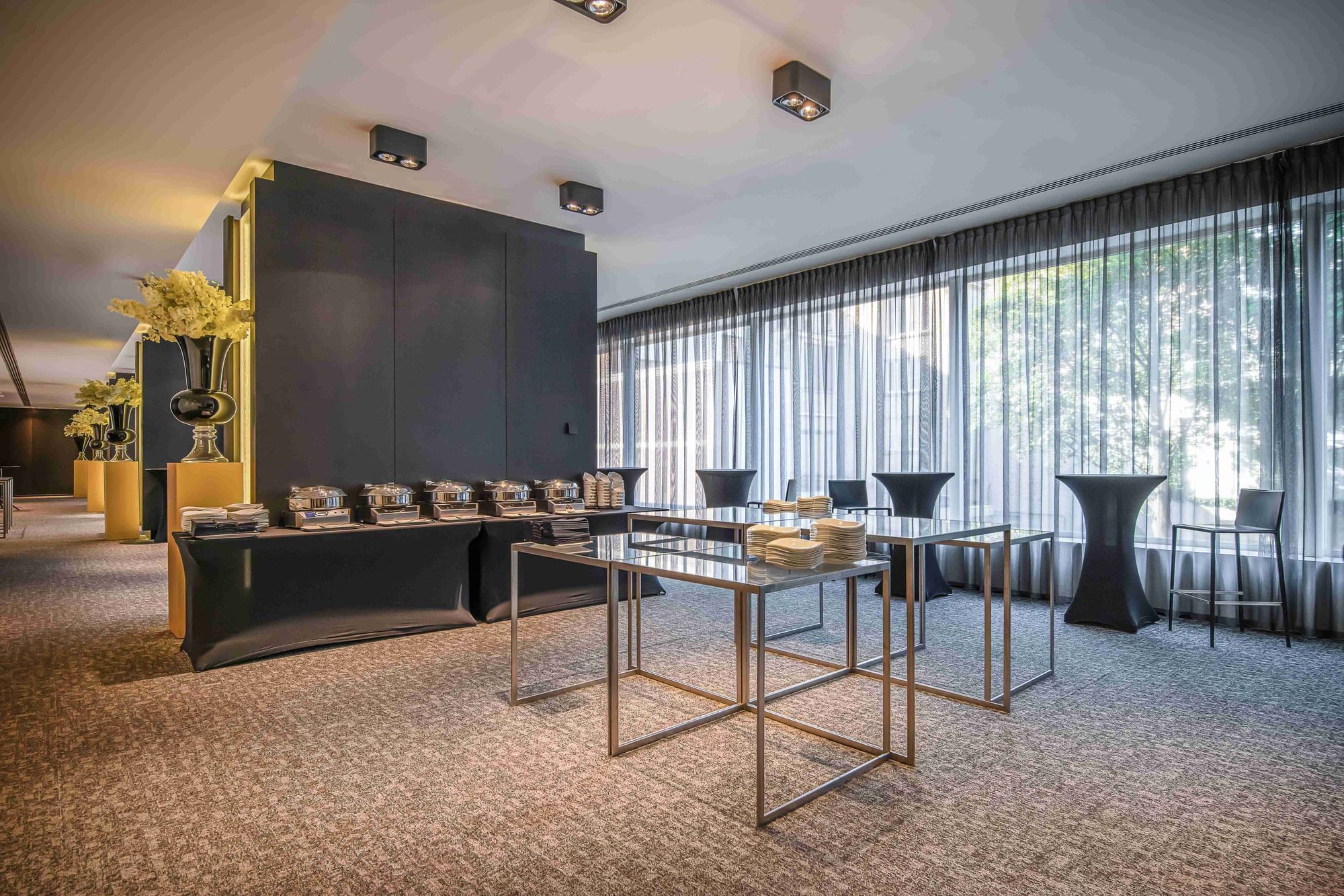 Interior of a modern banquet room with carpet floor & buffet table set for an event at The Hotels Brussels