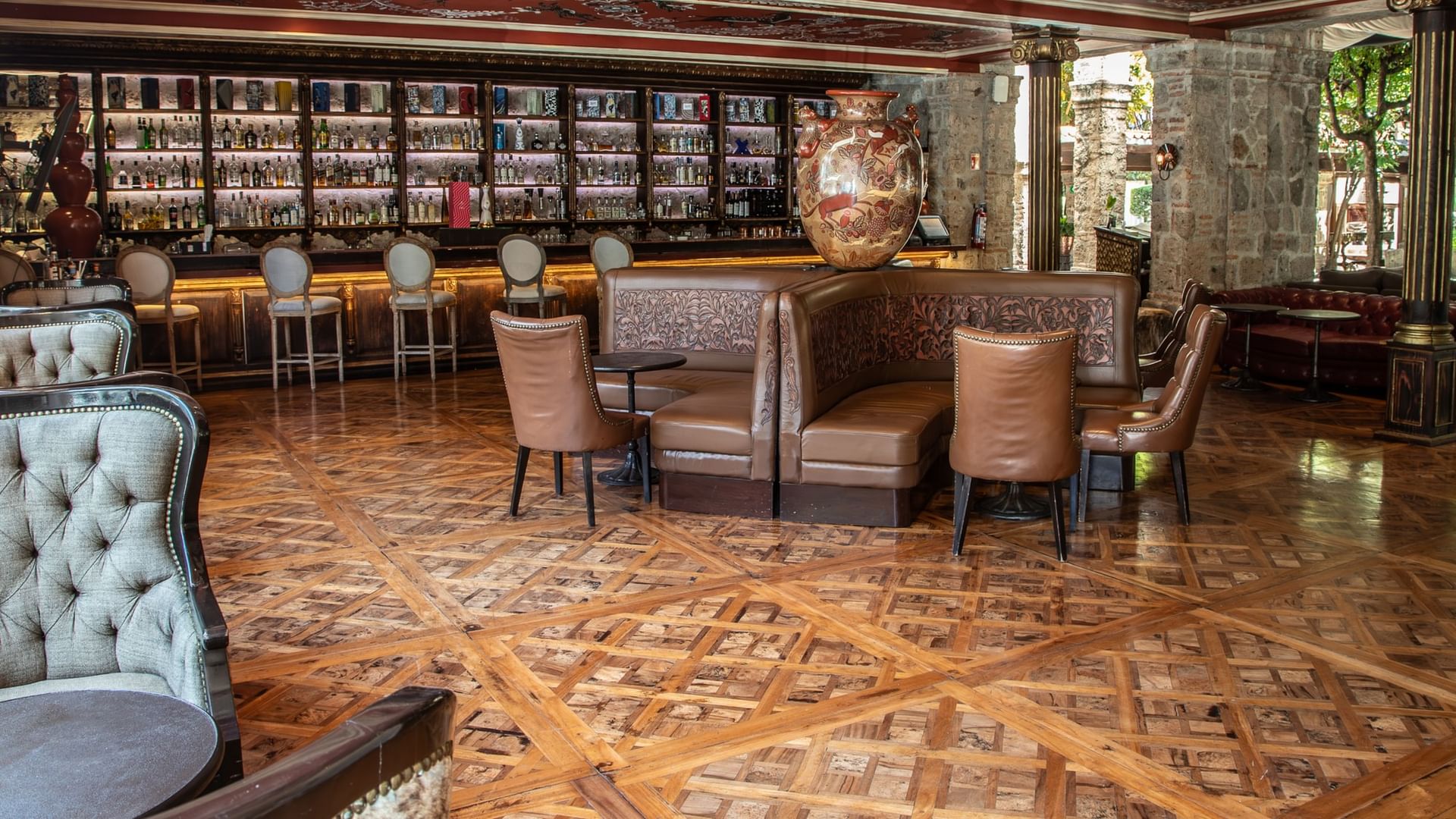 Elegant restaurant interior with intricate parquet flooring, leather seating, and a backlit bar at Quinta Real Guadalajara