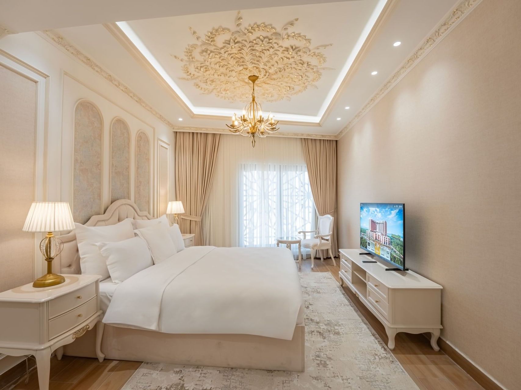 Elegant bedroom with large bed, TV, and chandelier at World Heart Hotel Baghdad.