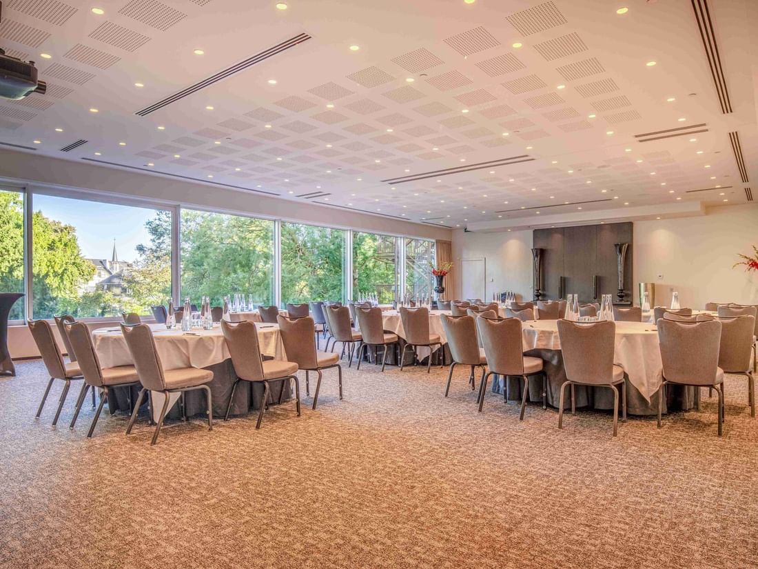 Park Ballroom with arranged tables, chairs, and large windows overlooking greenery at The Hotel Brussels