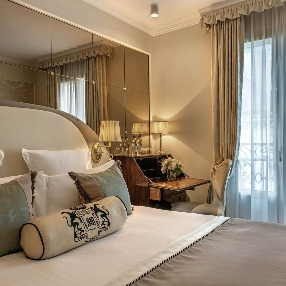 Élégante chambre simple supérieure avec un grand lit, des oreillers à motifs floraux et un bureau raffiné à l'Hôtel Westminster - Paris.