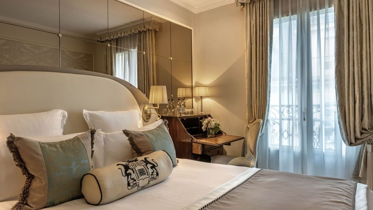 Élégante chambre simple supérieure avec un grand lit, des oreillers à motifs floraux et un bureau raffiné à l'Hôtel Westminster - Paris.