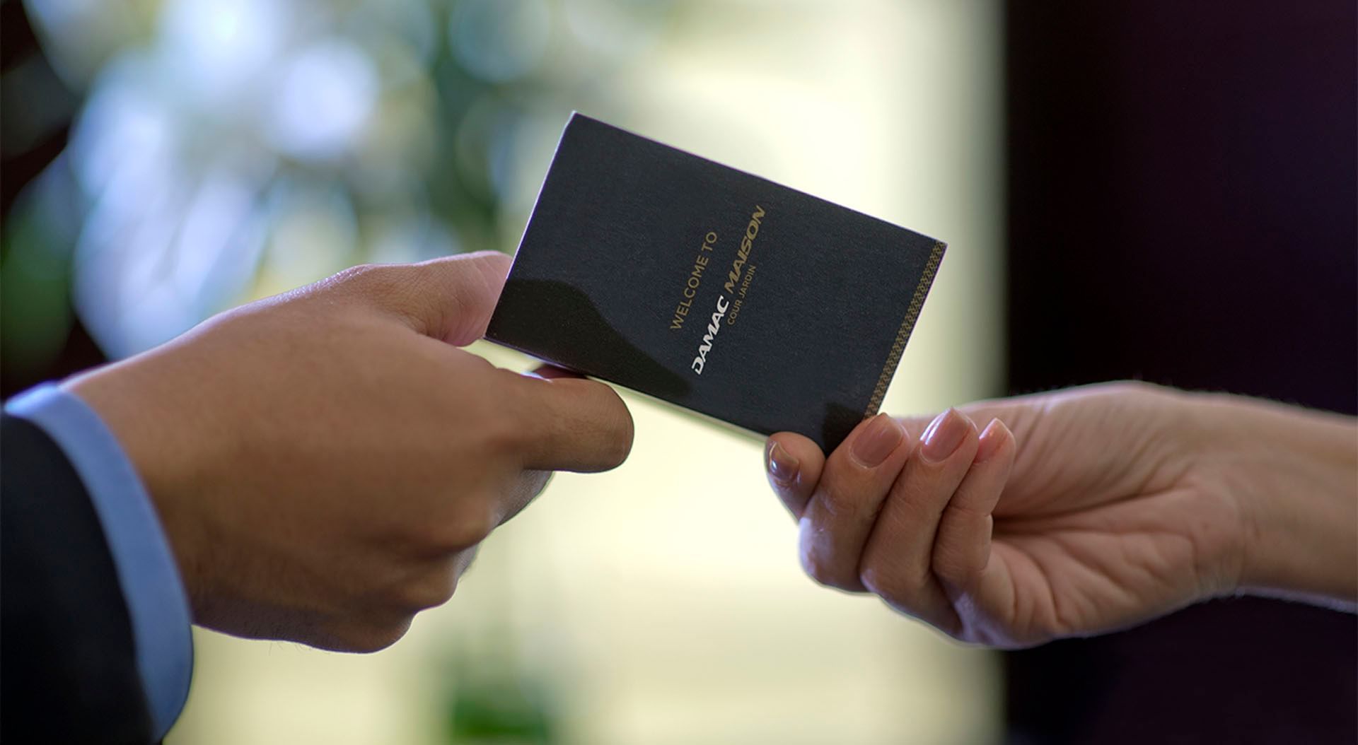 Two hands exchanging business card at DAMAC Hotels & Resorts
