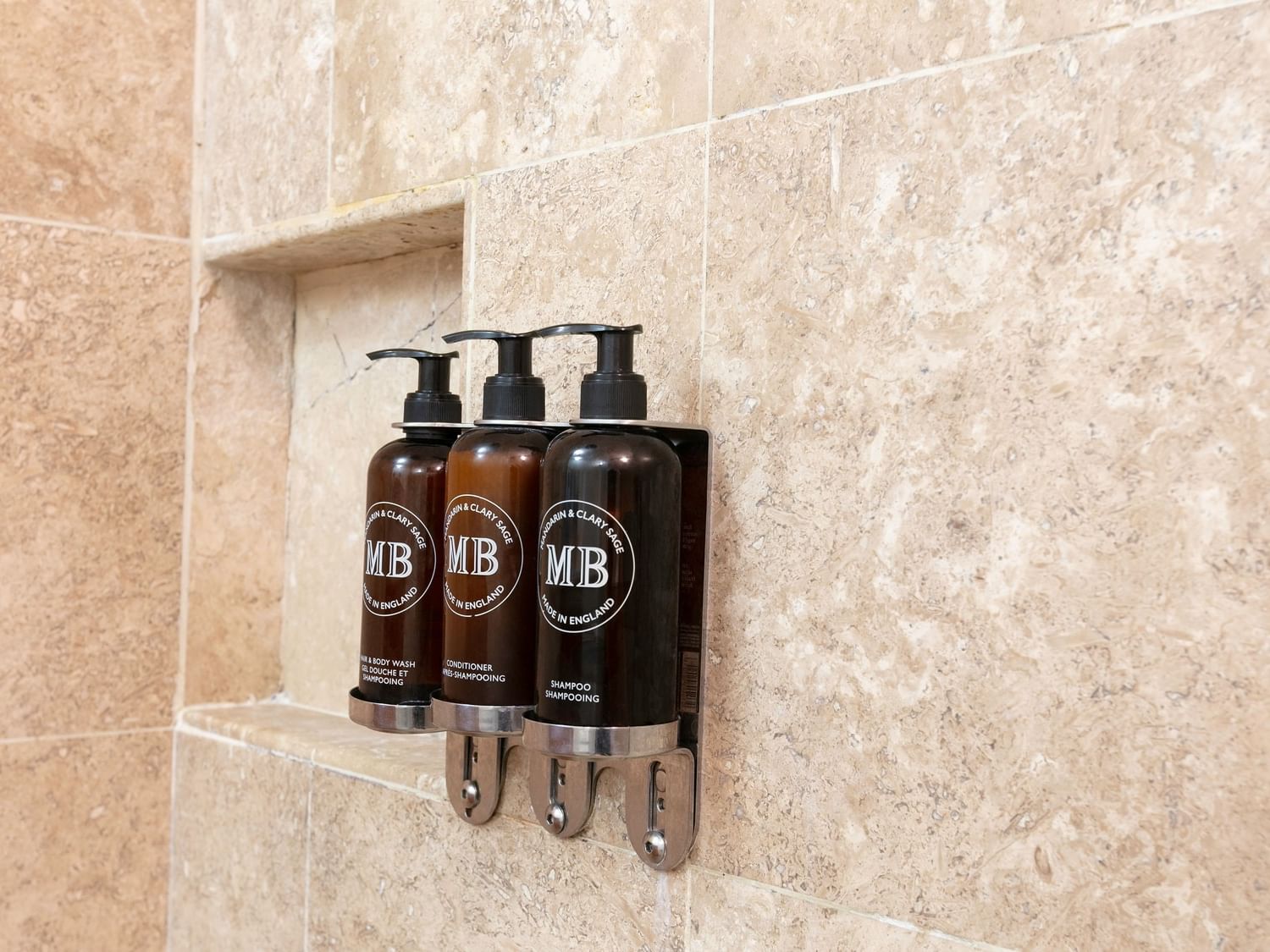 Tres botellas de productos de baño en la ducha de la habitación Camino Real Club King en Camino Real Guadalajara, Zapopan.
