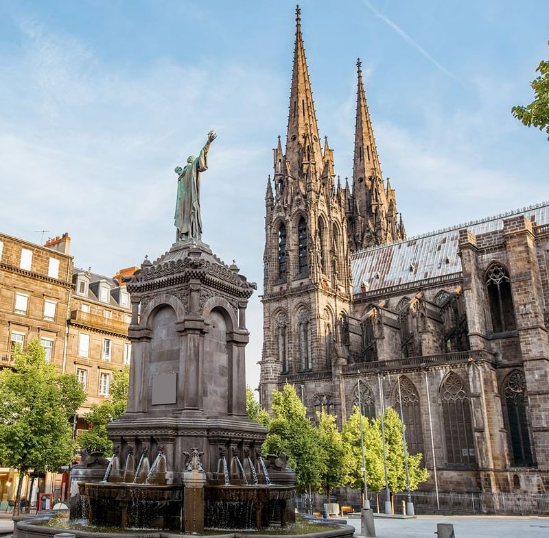A statue in front of a majestic cathedral near Oceania Hotels