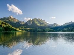 Vibrant landscape near Hotel des Innovations showcasing green mountains reflecting in Schwarzsee, a natural moorland lake