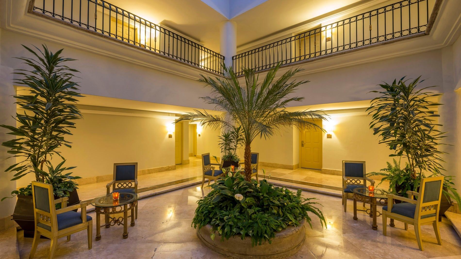King Presidential Suite courtyard featuring a large palm tree and seating arrangements at Camino Real Puebla Angelopolis