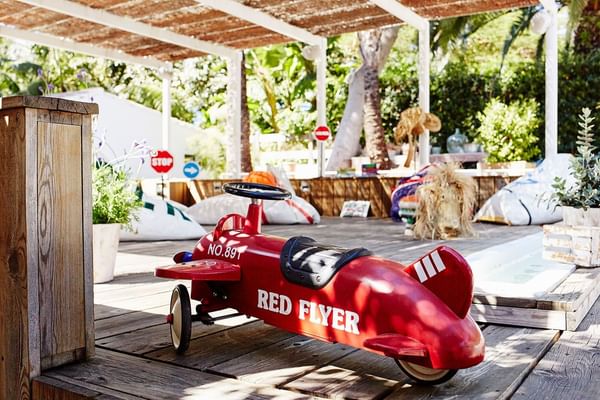 Red Red Flyer airplane pedal toy on a sunny wooden deck at Marbella Club’s Kids Club