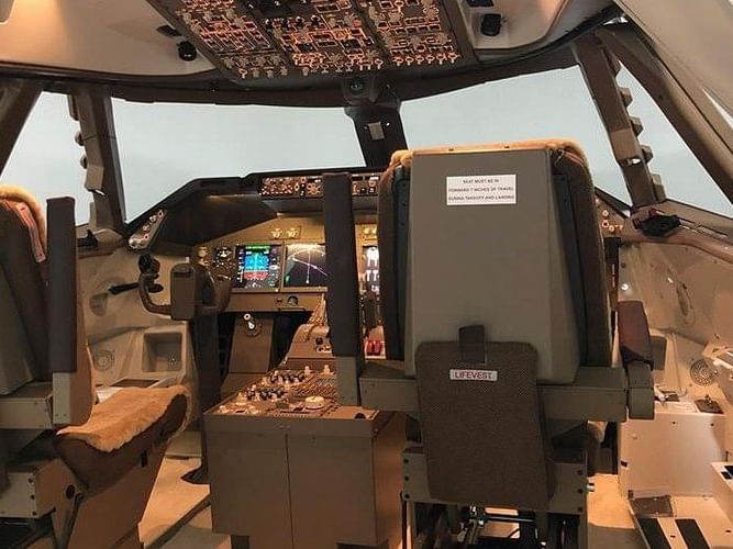 Cockpit interior featuring pilot seats, control panels, screens, and warning labels in Aviax near Saujana Hotel Kuala Lumpur