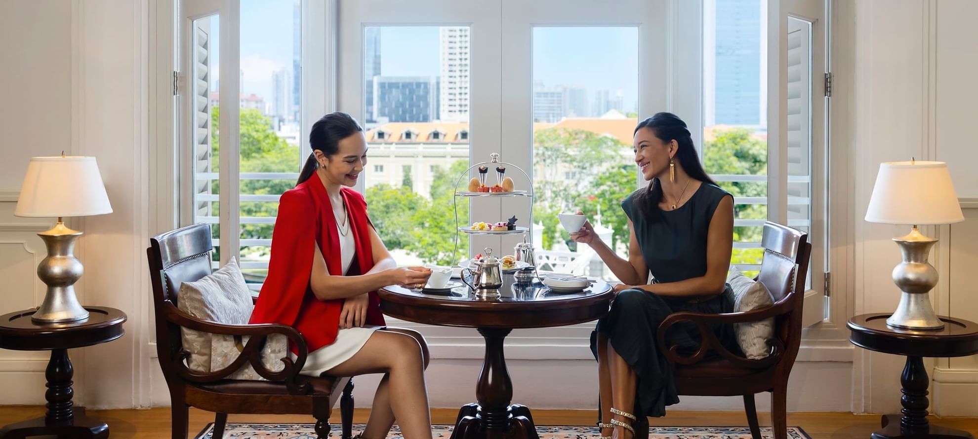 Two ladies enjoying high-tea with a city backdrop at Fullerton Singapore