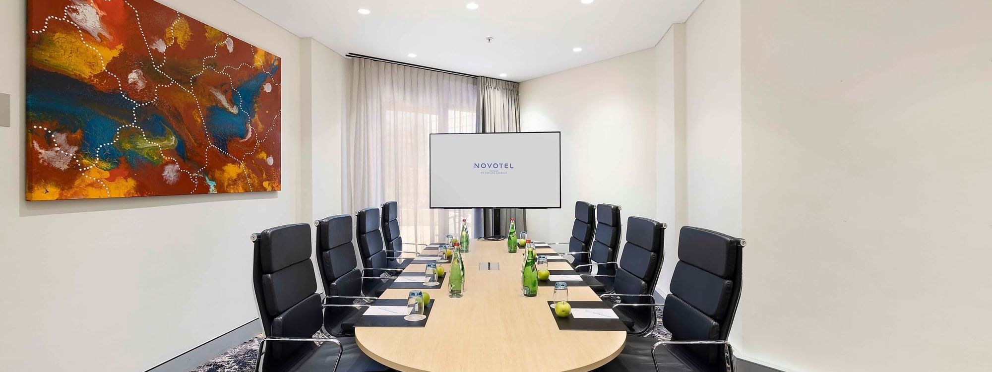 Boardroom set-up facing the projector screen in The Riverina Boardroom at Novotel Sydney on Darling Harbour