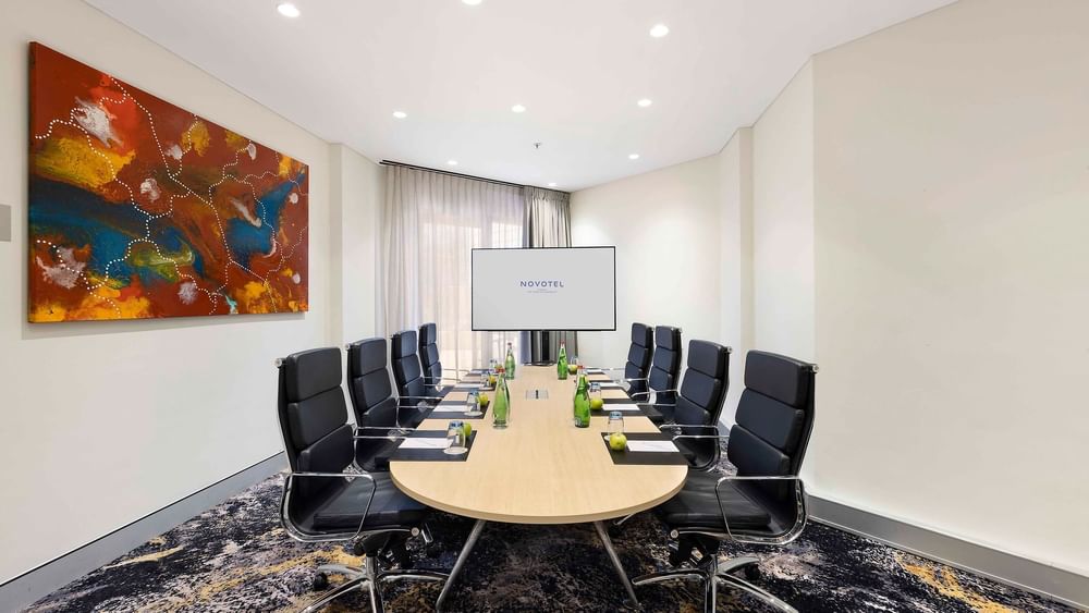 Boardroom set-up facing the projector screen in The Riverina Boardroom at Novotel Sydney on Darling Harbour