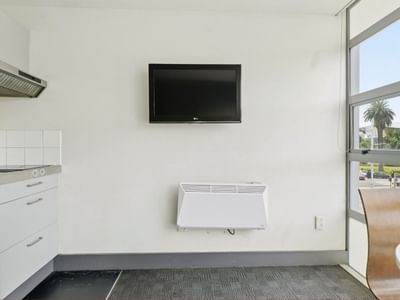 Kitchen area with TV, heater, and large window at Student Living Auckland - Beach.