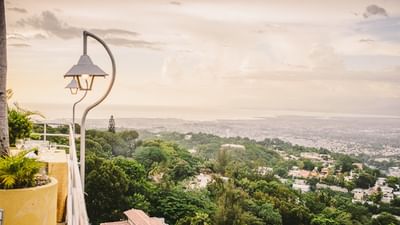 Ornate lamp post by a stone balcony overlooking the city and coastline at sunset at Hotel Montana Haiti