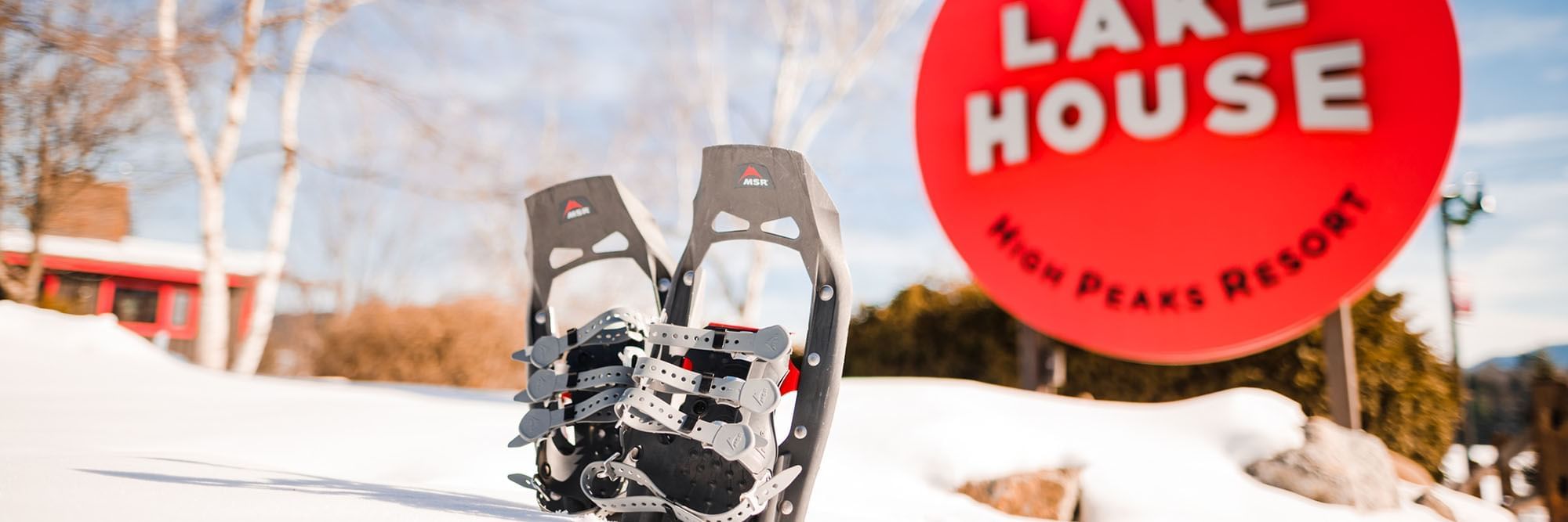 Snowshoes in the snow in front of the Lake House sign.