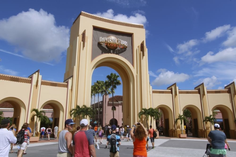 The entryway to Universal Studios Florida on a beautiful day with blue skies and people milling around. Try park-hopping at Universal Orlando.