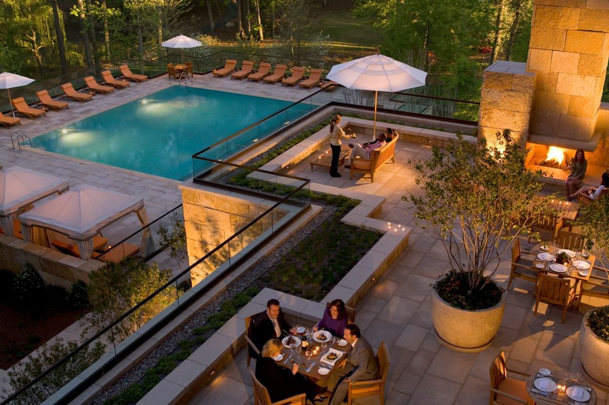 People enjoying dinner in the terrace overlooking the pool & trees at Umstead Hotel and Spa