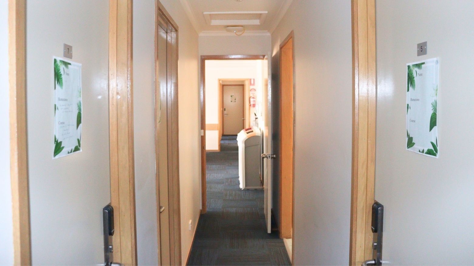 Hallway view with doors and tropical decor posters at La Trobe University Terraces.