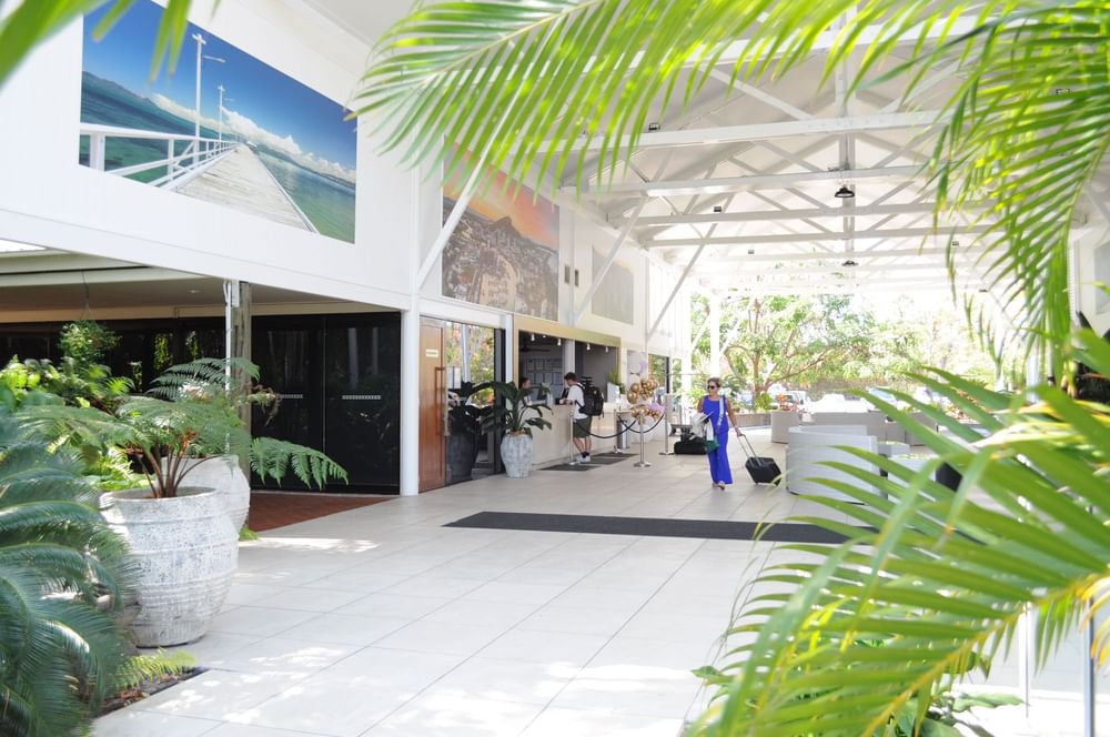 Open lobby featuring large artwork, potted plants & person walking with a suitcase at Mercure Townsville