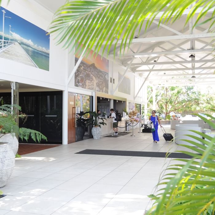 Open-air lobby with tropical plants, wall art and reception at Mercure Hotel Townsville