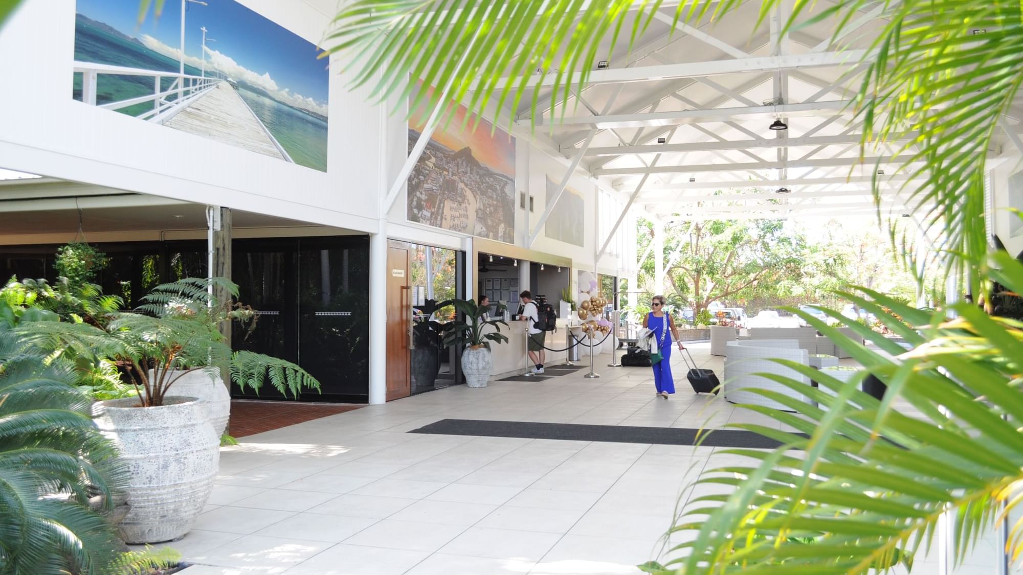Open-air lobby with tropical plants, wall art and reception at Mercure Hotel Townsville