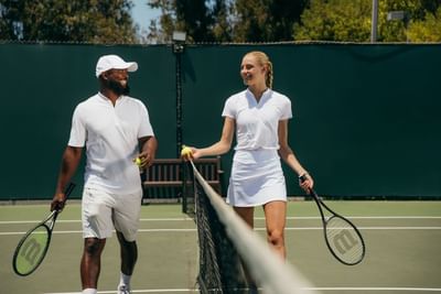 A couple playing tennis on the court at Luxe Sunset Boulevard Hotel