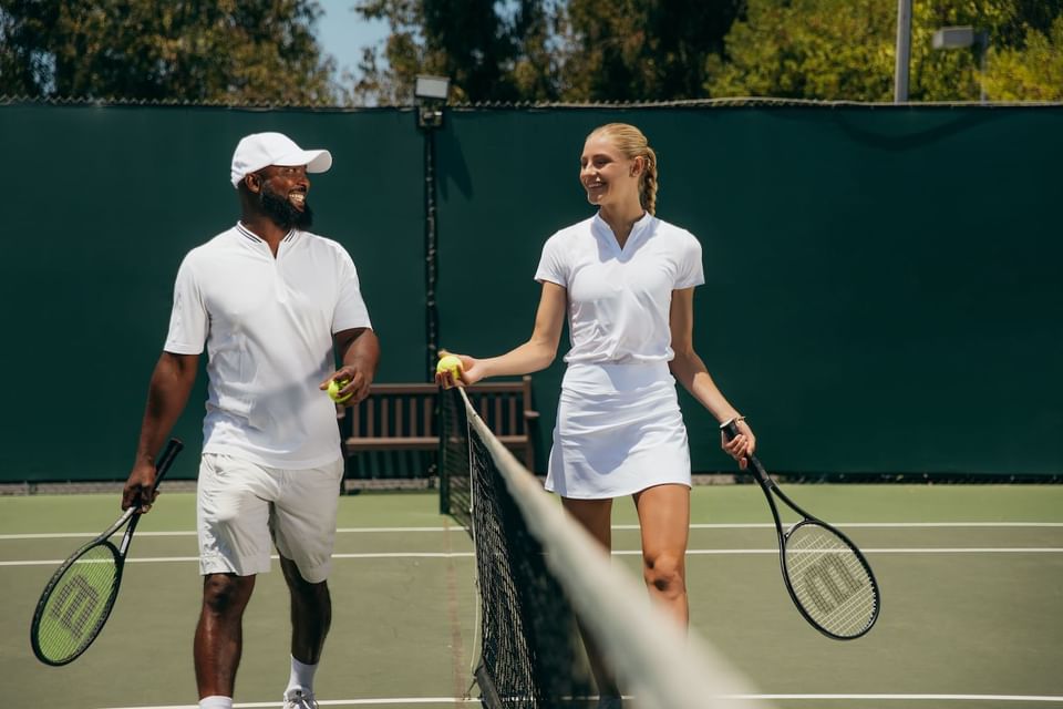A couple playing tennis on the court at Luxe Sunset Boulevard Hotel