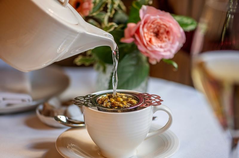 Porcelain teapot pouring herbal tea into a cup at The Capital Hotel, Apartments and Townhouse